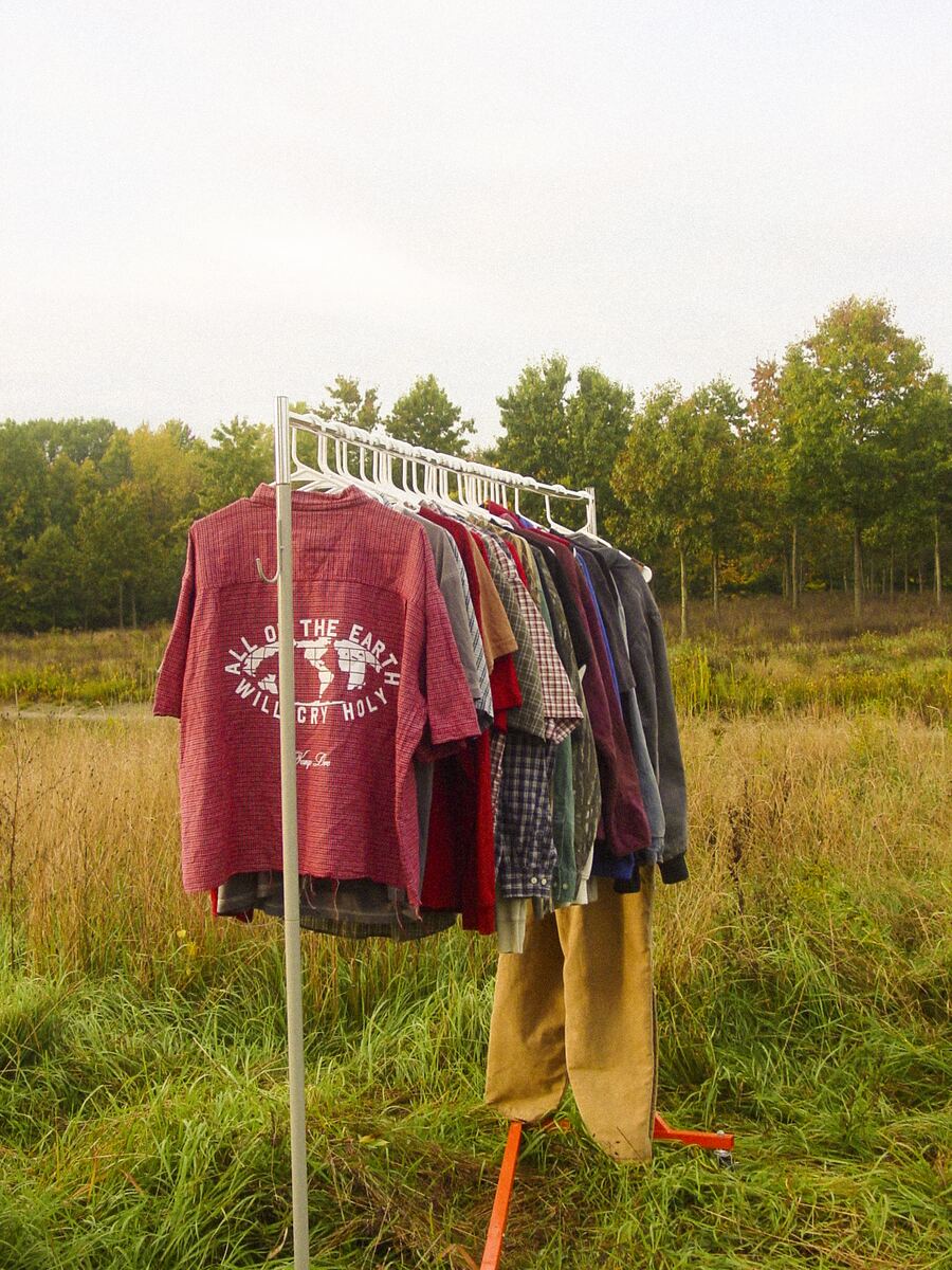 A clothing rack of the Kamp Love thrift line standing in a field